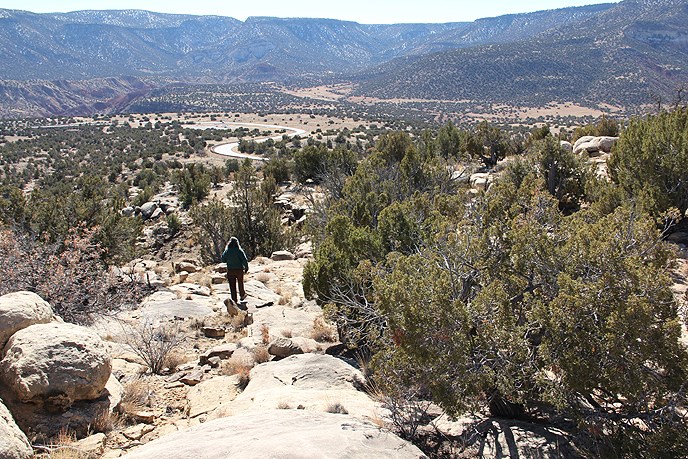 Rocky terrain in the foreground lead to scenery of a road and mountains, one person walks on the rocks Rocky terrain in the foreground lead to scenery of a road and mountains, one person walks on the rocks