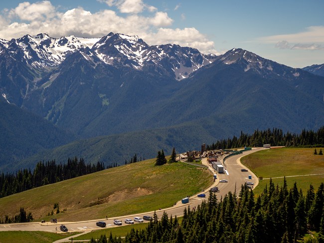 A parking lot and building burn site with snowcapped peaks in the background.