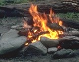 A small campfire burns, surrounded by a rock fire ring.