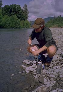 Backpacker filtering water out of river.