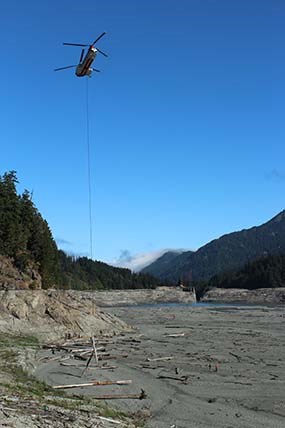 A helicopter drops wood onto the exposed landscape that was once Lake Mills