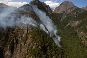 Smoke billows from the Constance Fire as it burns across a mountainside