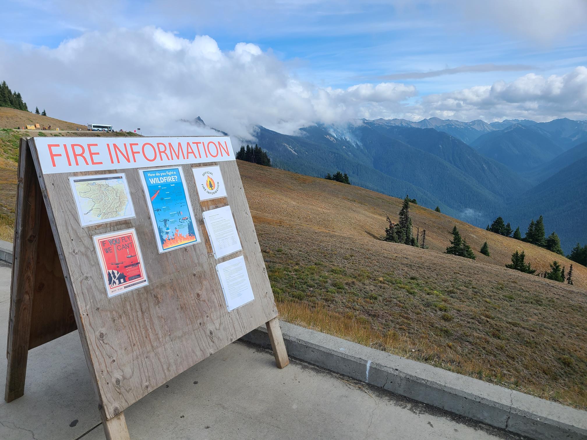 Eagle Point Fire w board 9-4 A fire info board with smoke plumes in the distance.