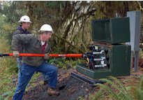 man using long orange pole to make electrical connection