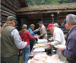 people, one in National Park Service uniform, serving themselves food from buffet line