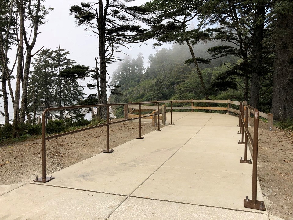 A paved path lined by new railings leads to an overlook over Ruby Beach.