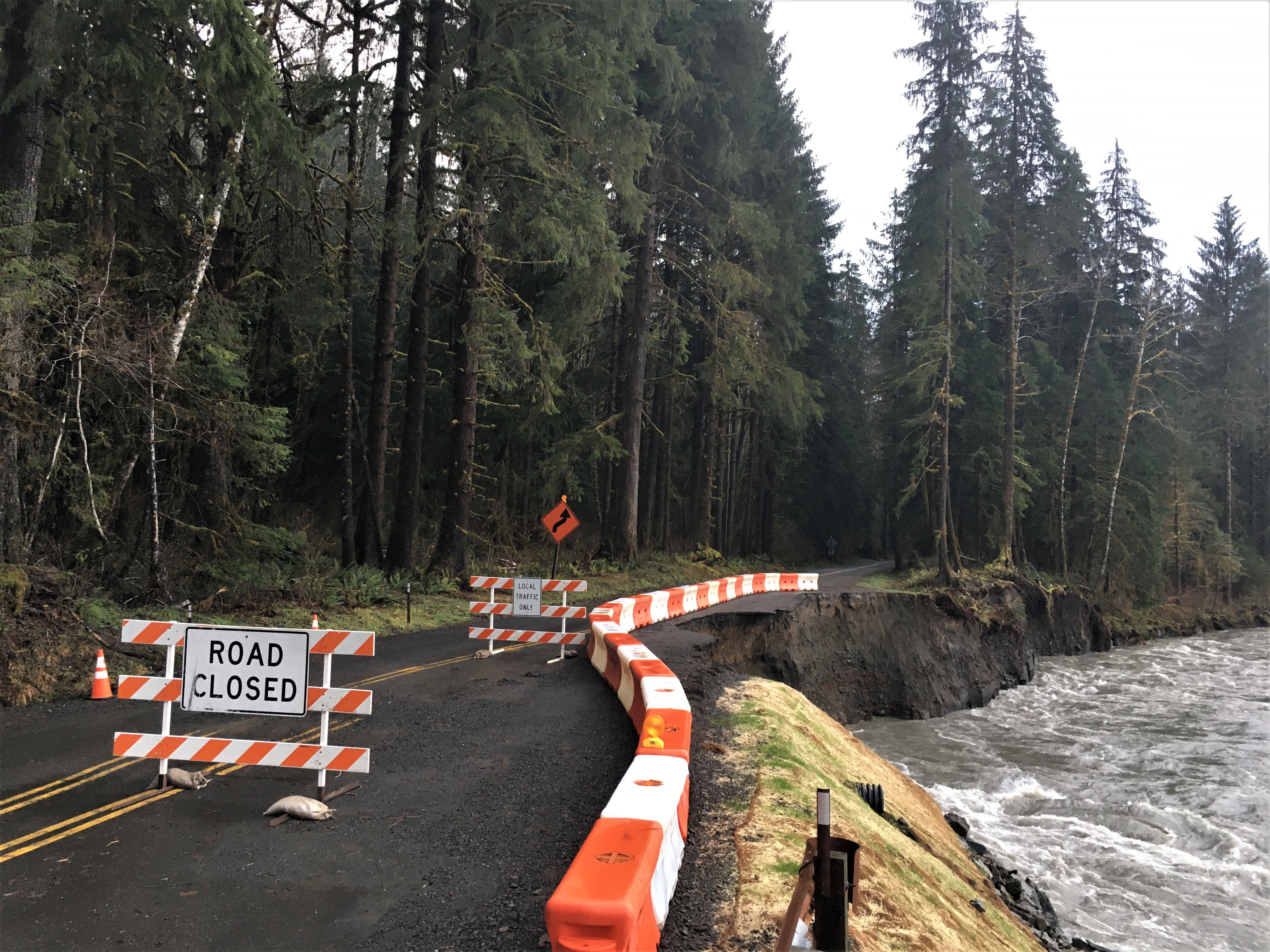 Road being washed out by a flooding river.