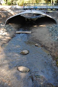 New culvert at Griff Creek, photographed while under construction. A temporary bridge is viewed at top of photo, and creek flowing through wide culvert.