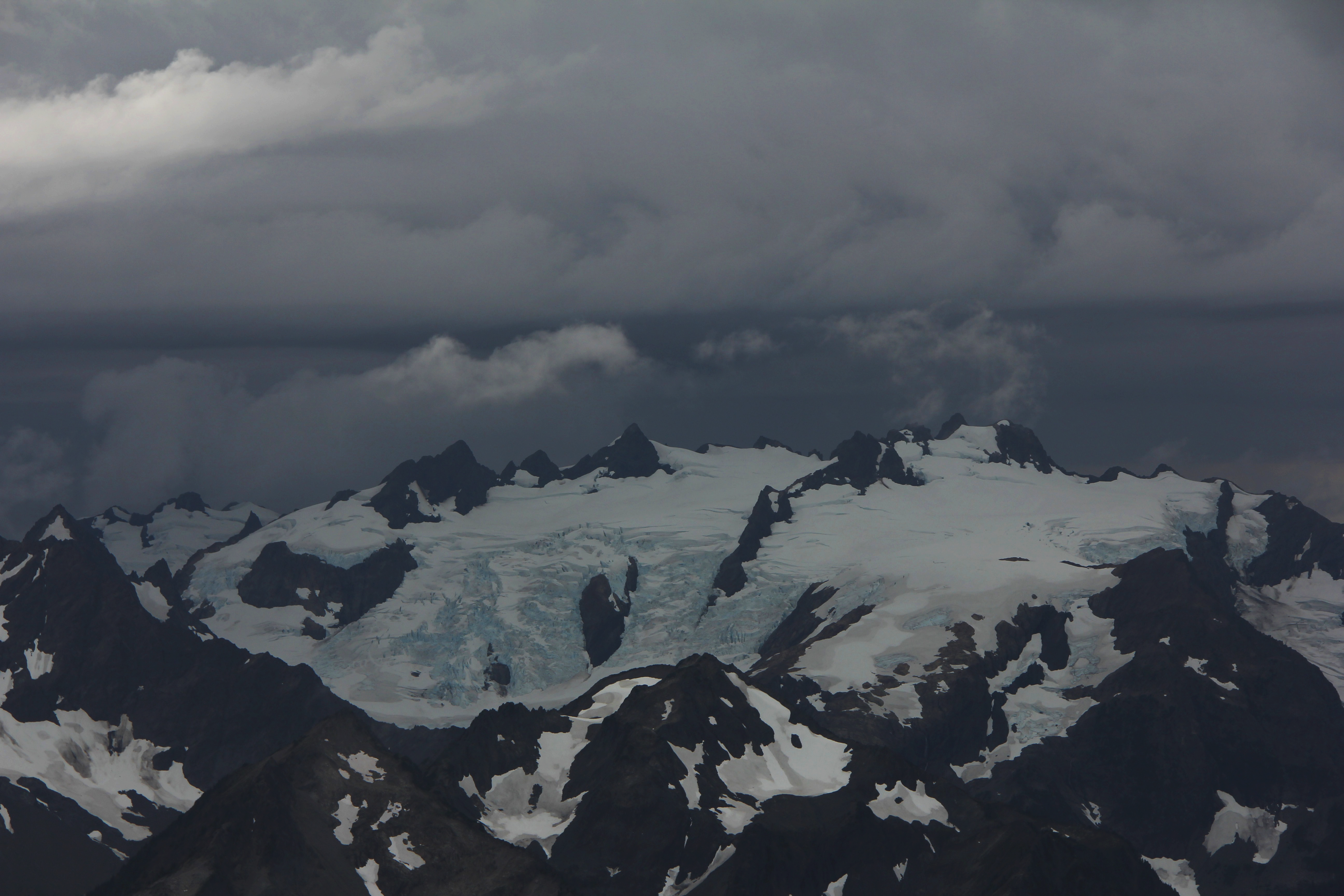 Large storm clouds over a snowy mountaintop.