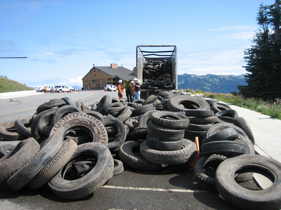 large pile of tires in a parking lot with truck in background