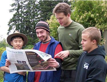 four young men reading a newspaper