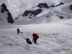 Climbers ascending Blue Glacier, with Mount Olympus towering in the background.