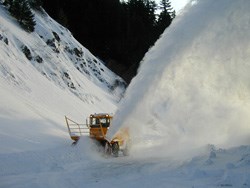 Snowplows blow snow off of roadway.