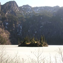 The frozen waters of Lake Angeles. An island sits in the middle of the lake and cliffs rise up from the far shore.