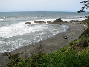 View from atop a bluff looking out to a beach with a small, rocky point.