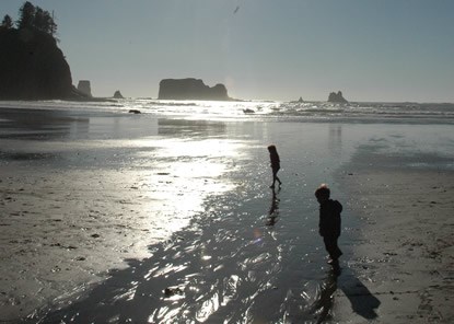 two small children on wide sandy beach, low sun angle