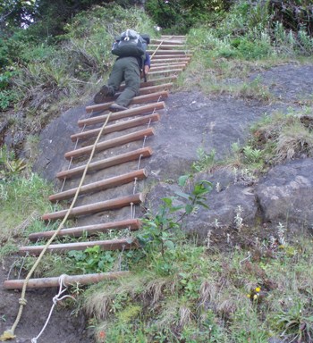 Backpackers climbing rope ladder