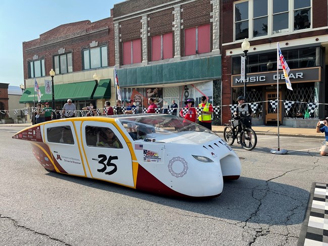 A solar car in front of a historic building.