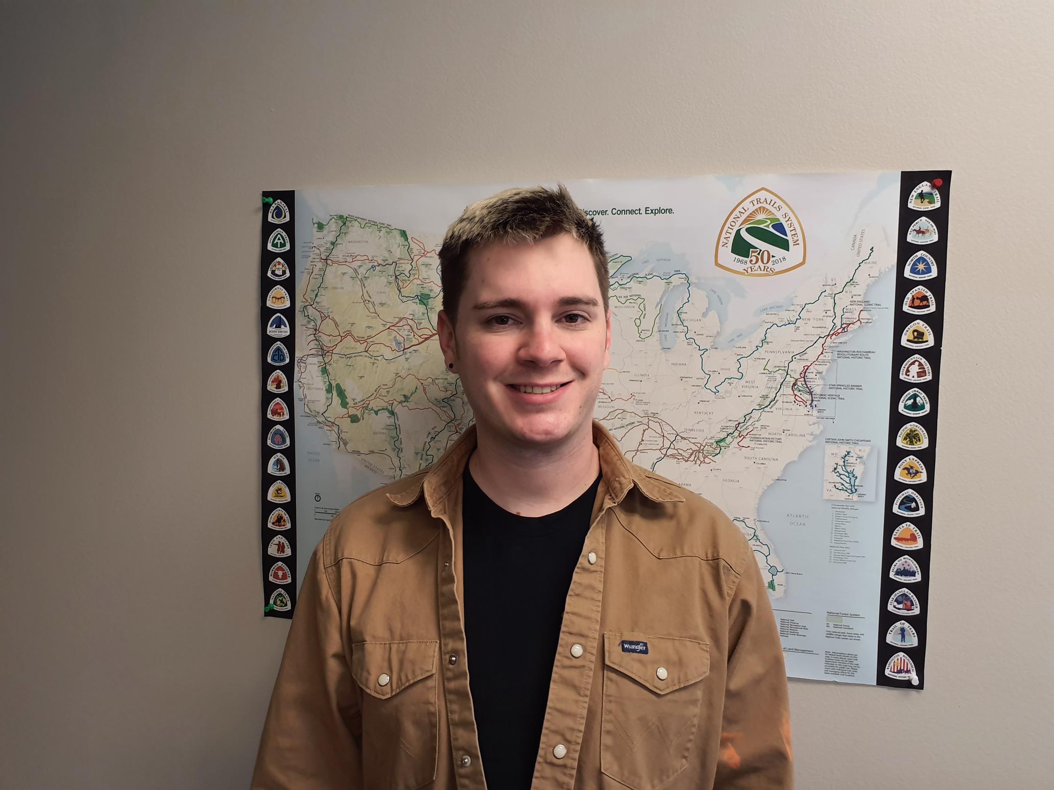 lt= A person stands in front of a map.