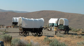Photo image of emigrant wagons at 
   Hill & the National Historic Oregon Trail Interpretive Center.