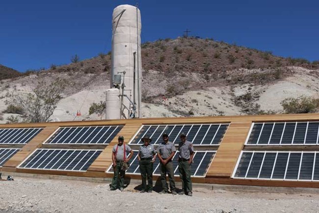 Work Crew standing in front of preserved historic solar panels in Death Valley.