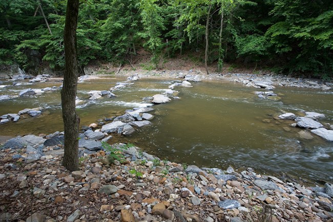 Rock Creek stream flows over several bands of rocks protecting buried infrastructure.
