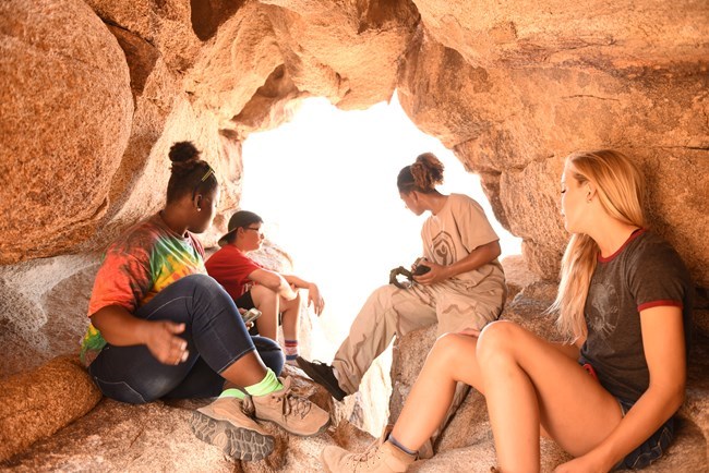 A group of young people sitting in a rock formation.