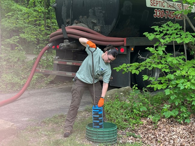 A person pulls an effluent filter from a septic tank.