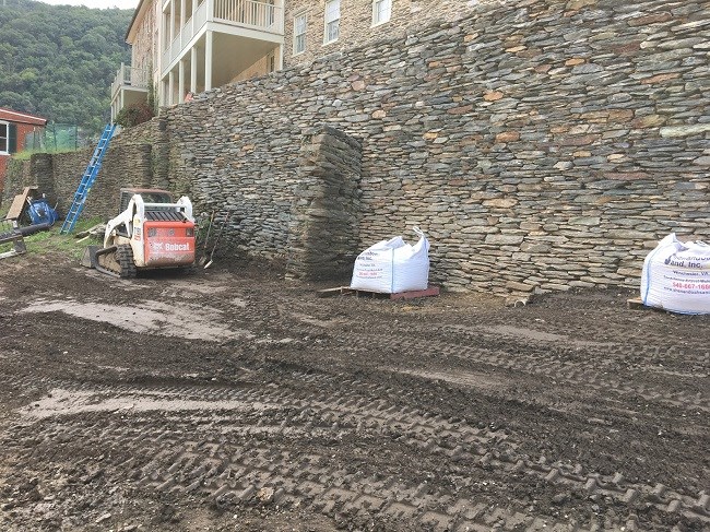 Two large retaining brick wall sections with large white bags and a small forklift.