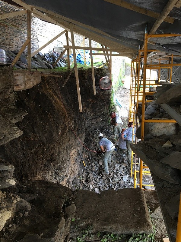 A large brick retaining wall with four HPTC members hammering