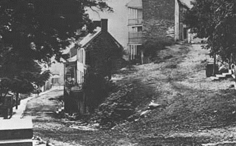 A black and white photo of a brick street on a hill