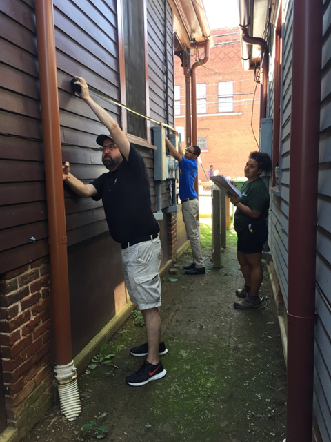 The architect team measuring the exterior of the building A group of people measuring the exterior of a building