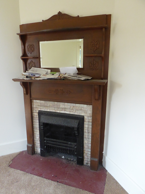 A historic fireplace mantle A brown fireplace mantle with a mirror on top