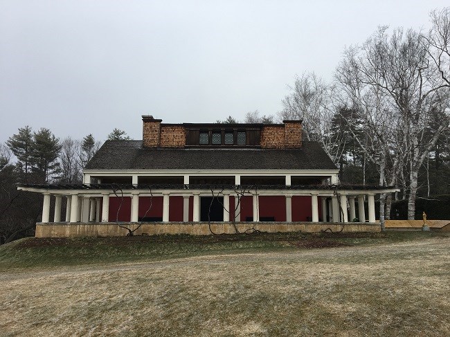 A white building with a red frontal exterior surrounded by white columns