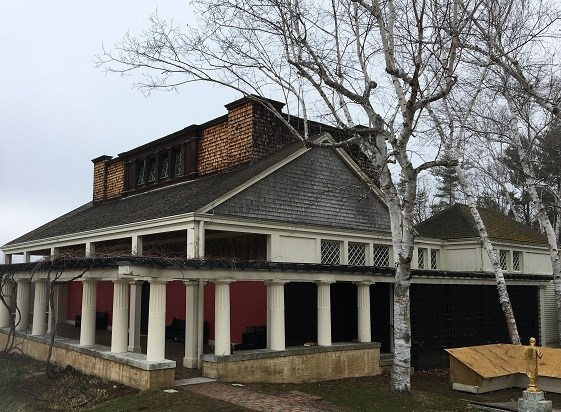 A white building with a grey roof surrounded by columns