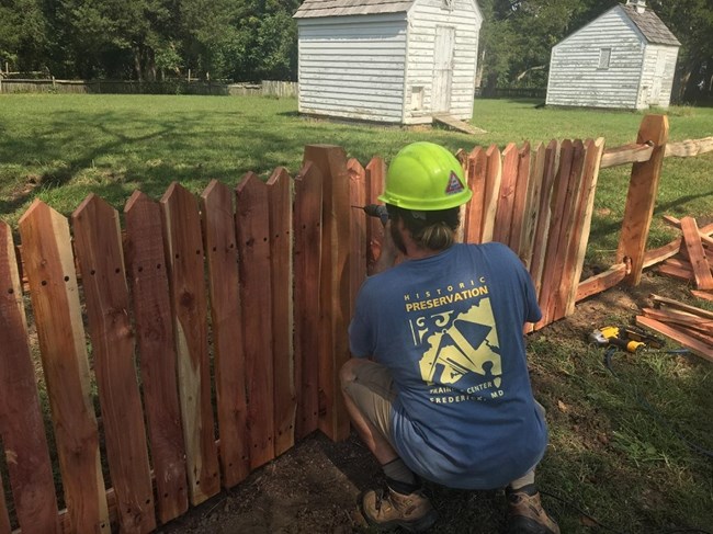 An HPTC member wearing a hard hat drilling a fence