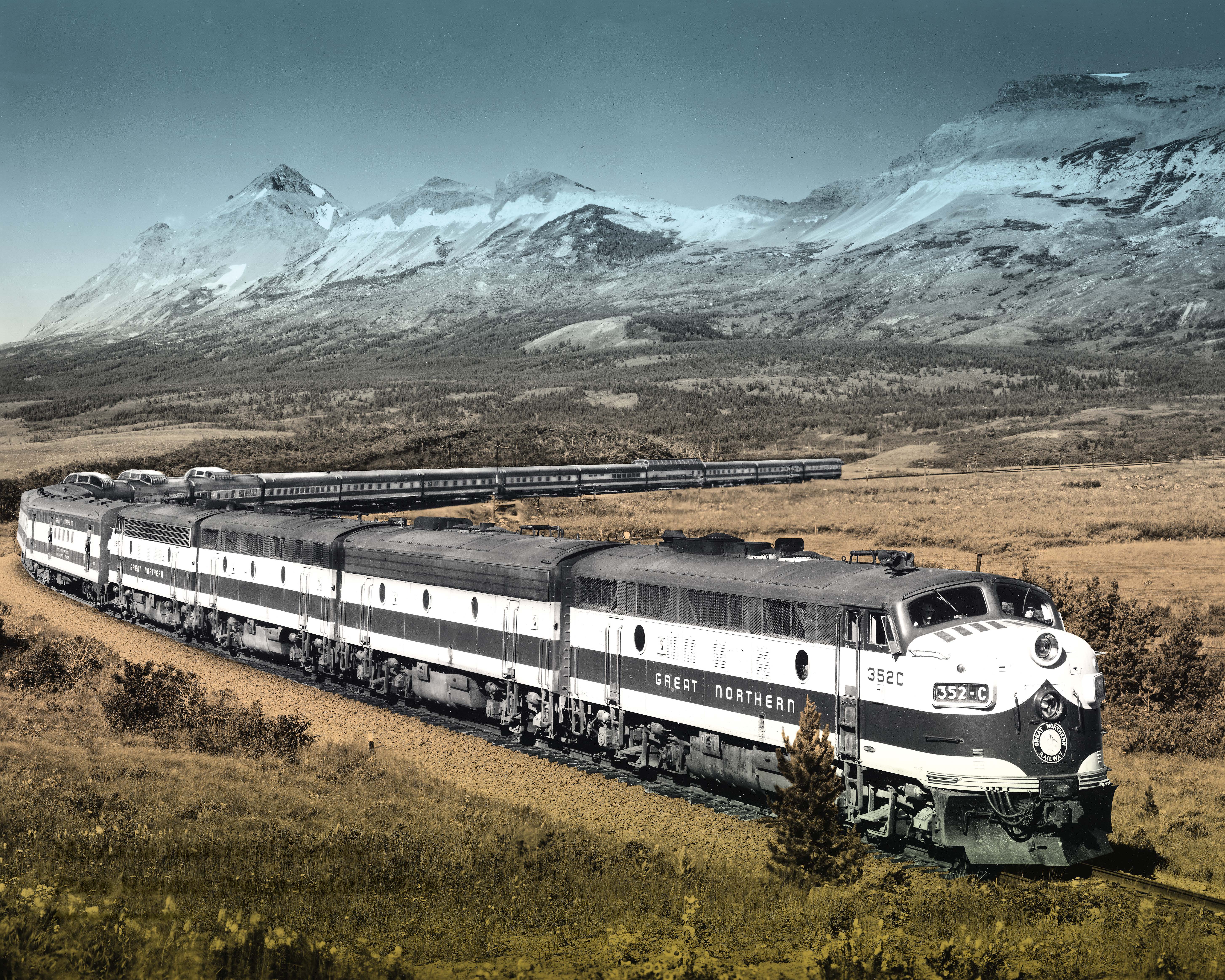 Great Northern’s Empire Builder Train bends around the track in front of Montana mountain range