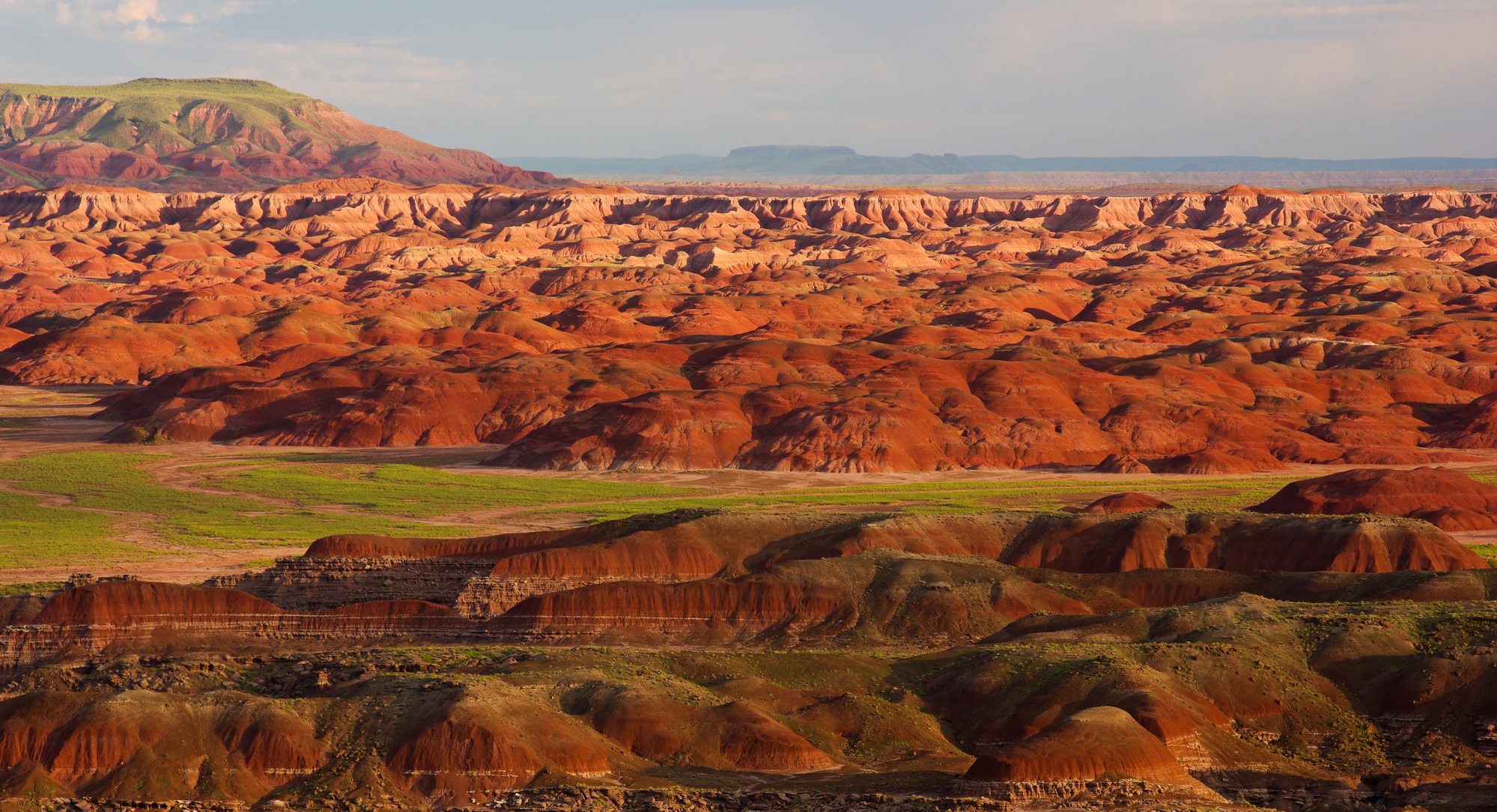 Red badlands with green grassy lowlands