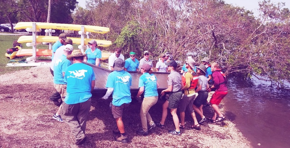 A crew of volunteers lifting a section of boardwalk from the shoreline