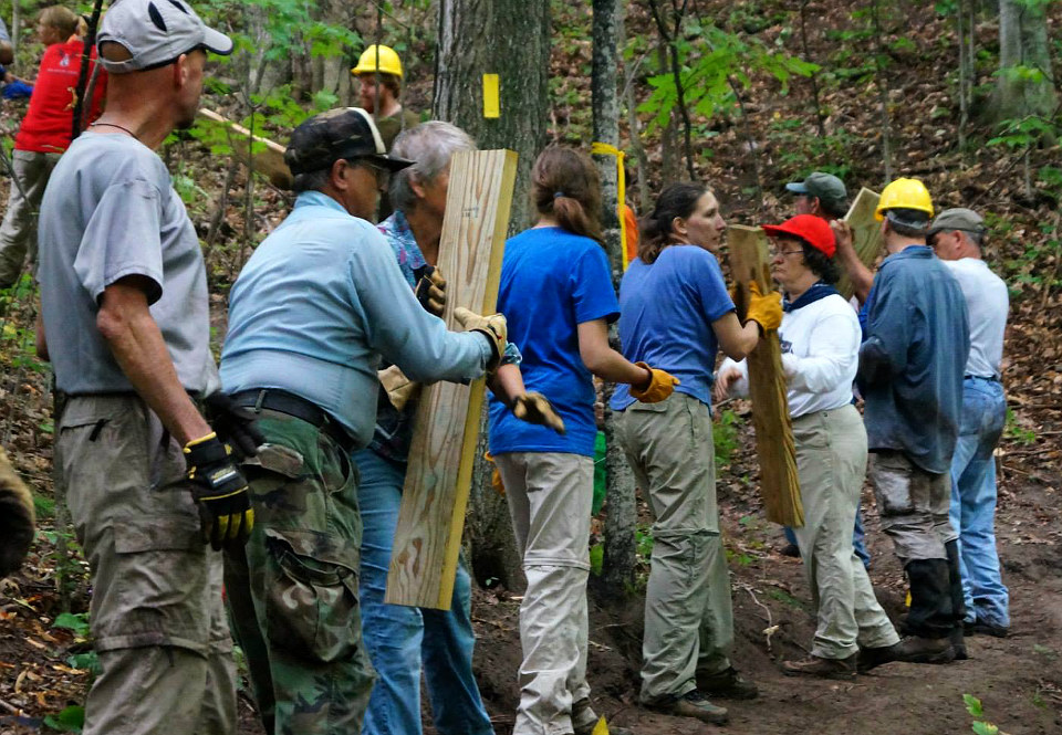 Group of volunteers passing boards as they build a trail Group of volunteers passing boards as they build a trail