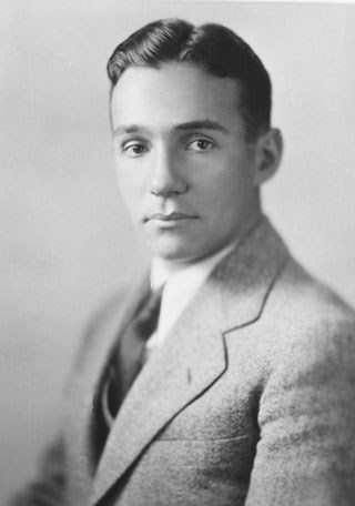 A black and white photo of a man in a suit and tie, looking at the camera
