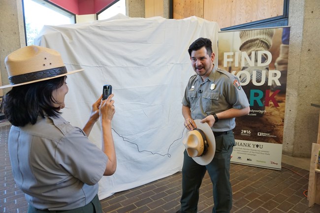 An NPS employee in uniform films another employee in uniform with a cell phone.