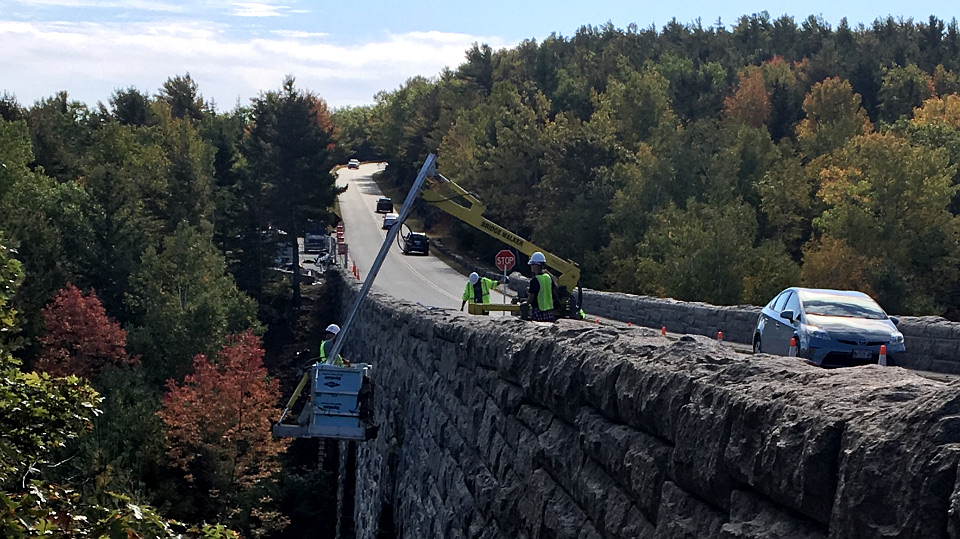 Construction worker in a bucket working on a large stone bridge