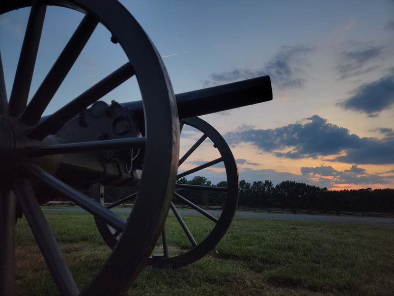 Morning light peaks through clouds over field, closeup of cannon in foreground Morning light peaks through clouds over field, closeup of cannon in foreground