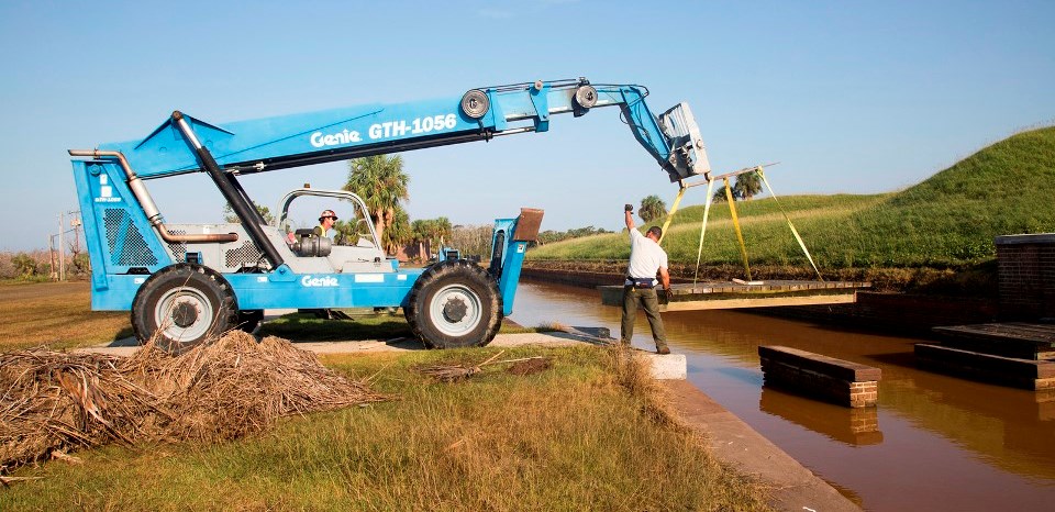 NPS staff use heavy equipment to replace a footbridge into the fort