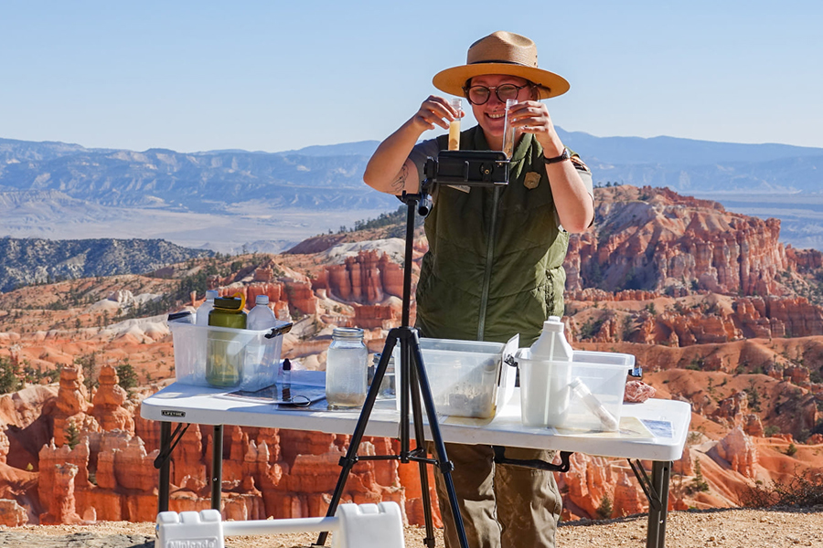 Park ranger giving a virtual program in front of a camera with canyon in background.