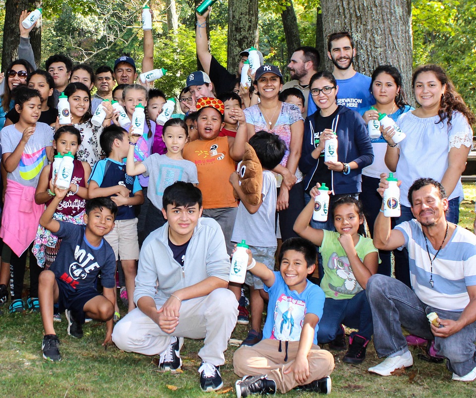 Youth group in the woods smiling with some holding water bottles