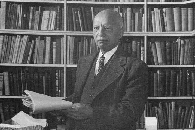 Black and white photograph of Carter G. Woodson in a library