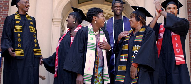 A group of students wearing graduation caps and gowns standing on stairs