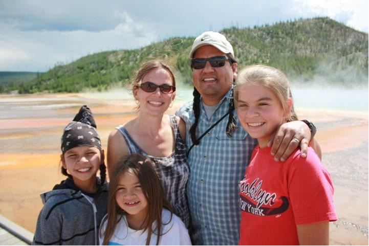 NPS Director Chuck Sams poses with his family in front of a hill covered in vegetation